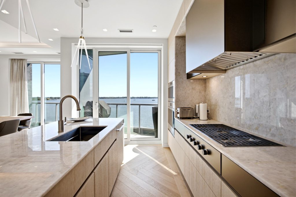 Penthouse kitchen with stone finishes and a lake view at 1 Edgewater Drive PH18, Toronto